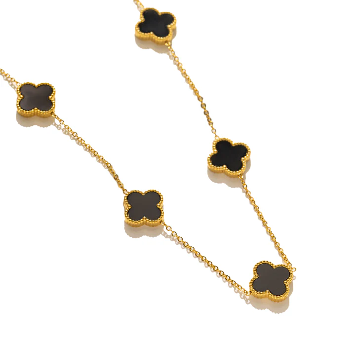 The Susan Rose S/S 5 Clover Necklace Black features five black four-leaf clover pendants with gold beaded edges on a stylish chain. Crafted from stainless steel, it adds an elegant touch to any outfit.
